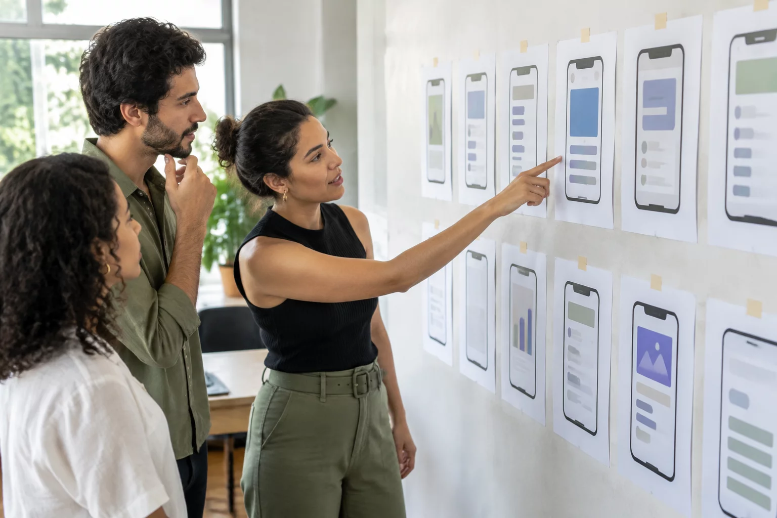 Equipe do estúdio diante de uma parede com telas de aplicativo impressas